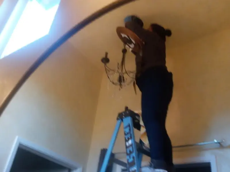 Electrician installing a chandelier in a Hurst residence